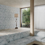 Modern living room with a large window, gray sofa, and decorative lamp with delicate floral wallpaper and upholstery.