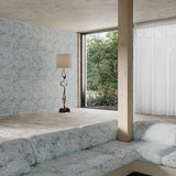 Modern living room with a large window, gray sofa, and decorative lamp with delicate floral wallpaper and upholstery.