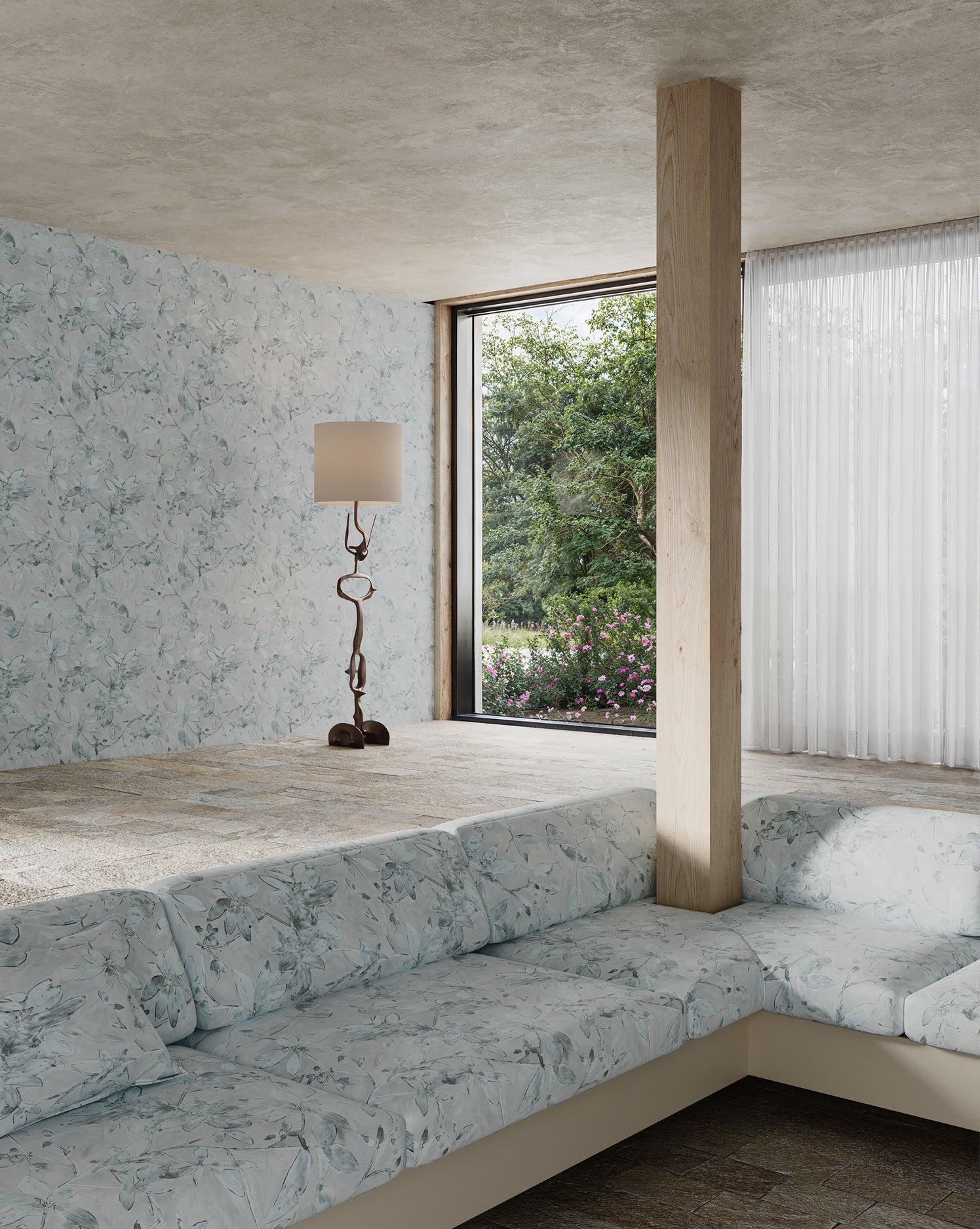 Modern living room with a large window, gray sofa, and decorative lamp with delicate floral wallpaper and upholstery.