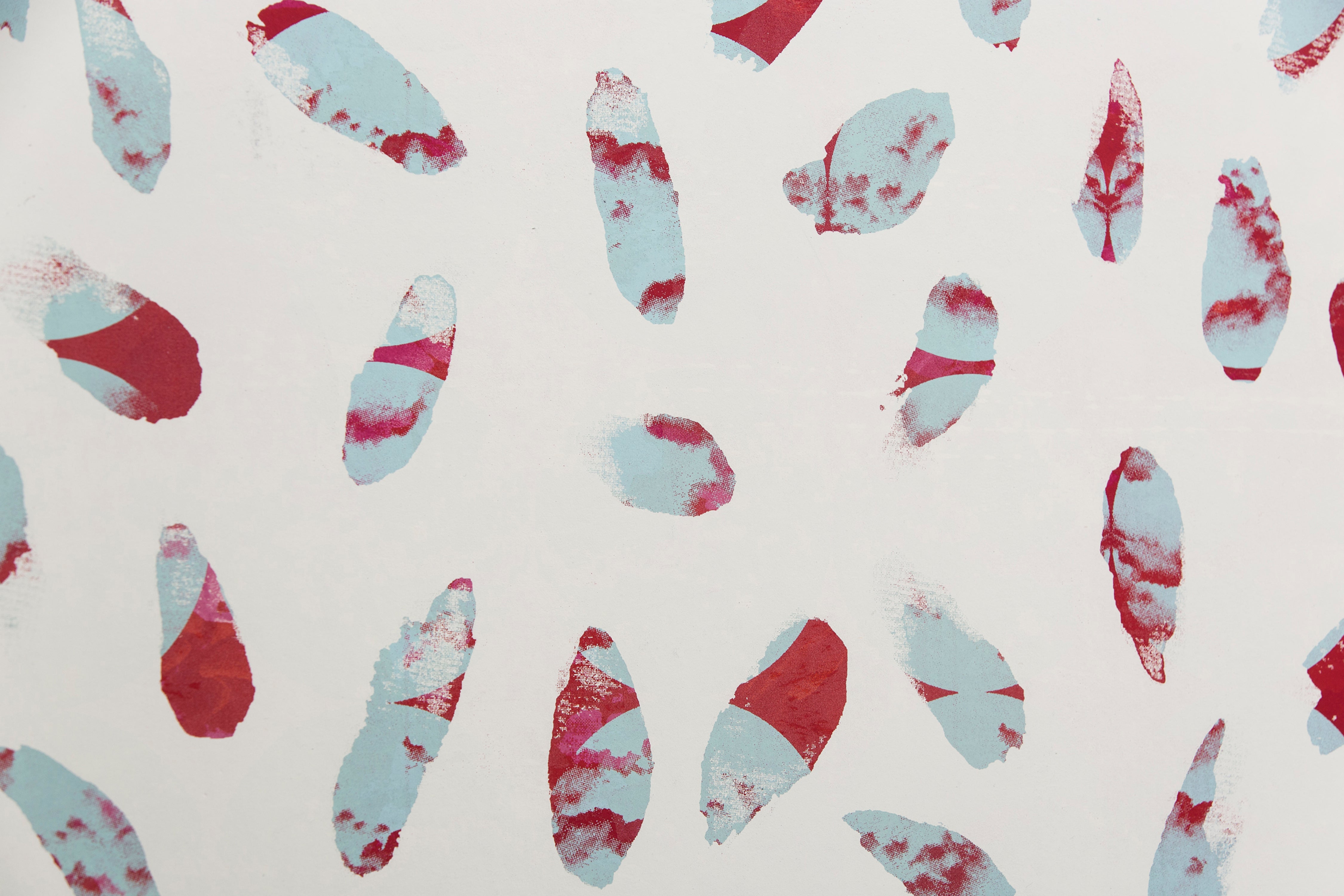 Detail of wallpaper in a playful paint blotch print in shades of red and blue on a cream field.