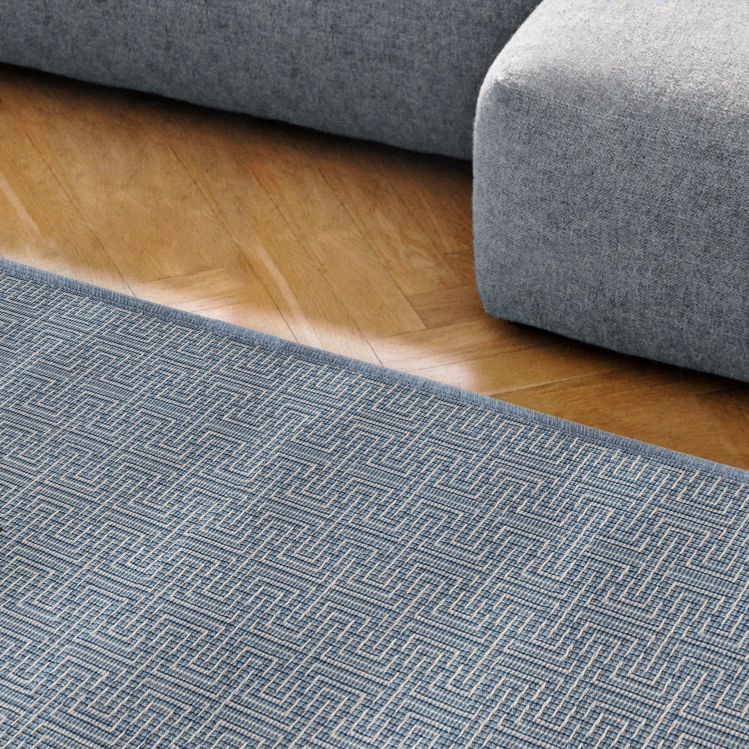 Modern blue couch next to a blue and white striped area rug on a wood floor. 