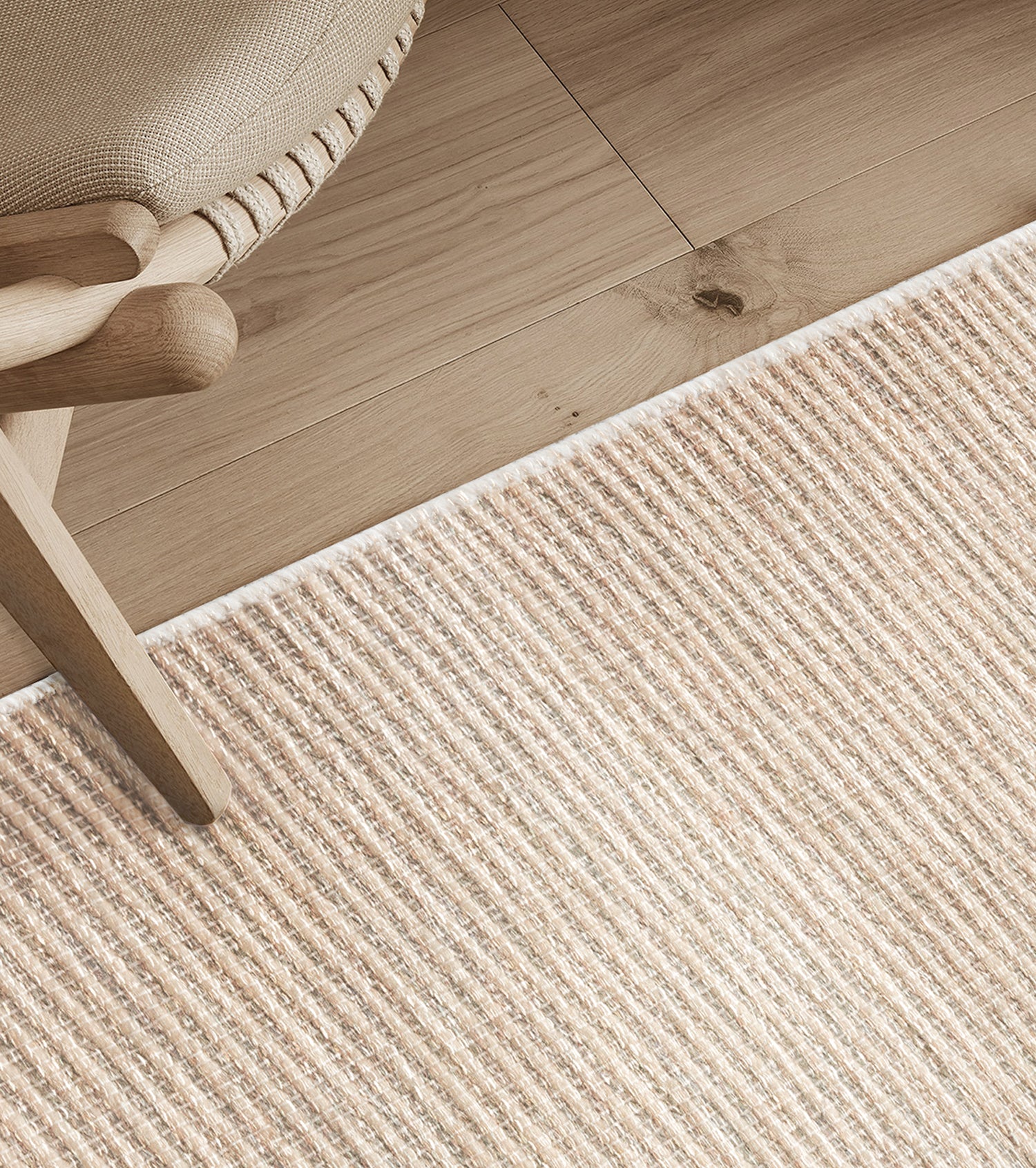 Detail shot of textural area rug on a wood floor with chair.