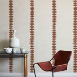 Modern interior with a red chair, black table, and decorative vase against a wall with abstract brown stripe