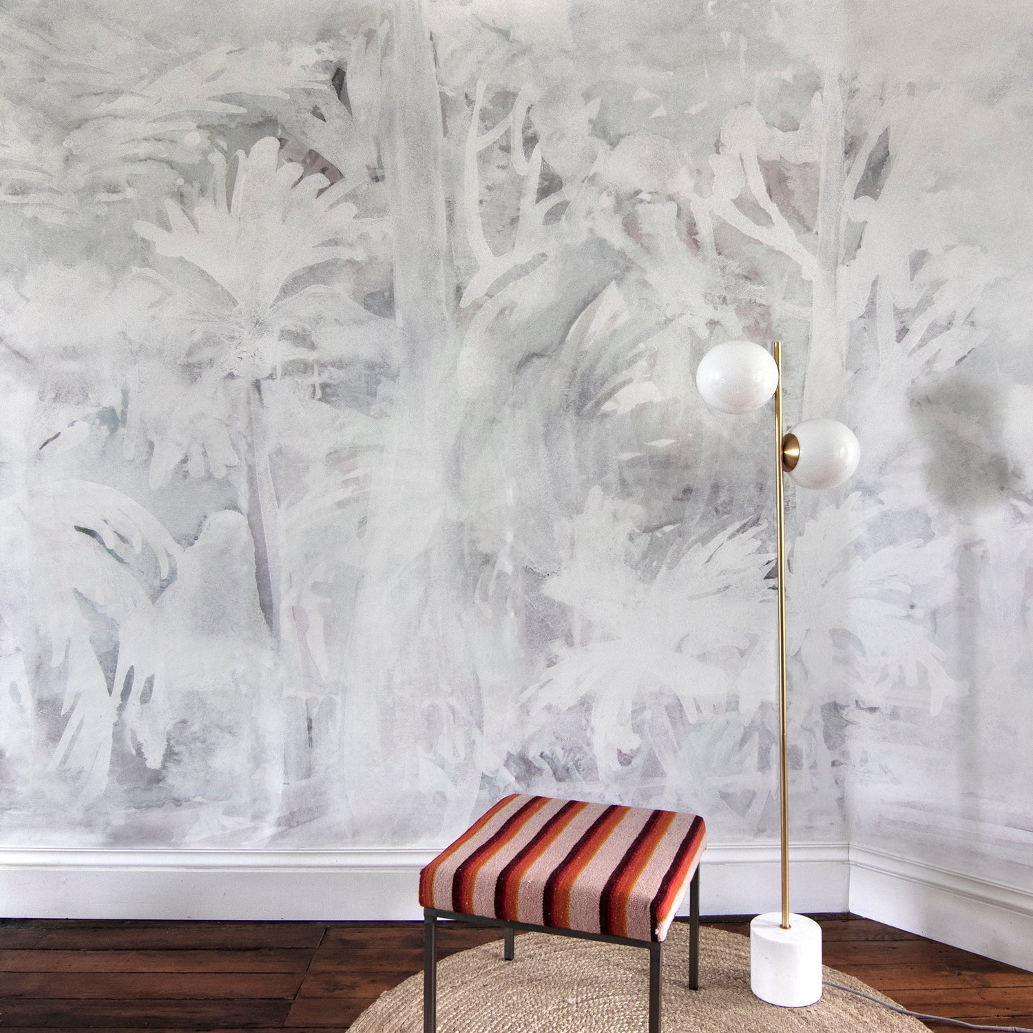 Room interior with abstract white wall design, striped stool, and floor lamp.