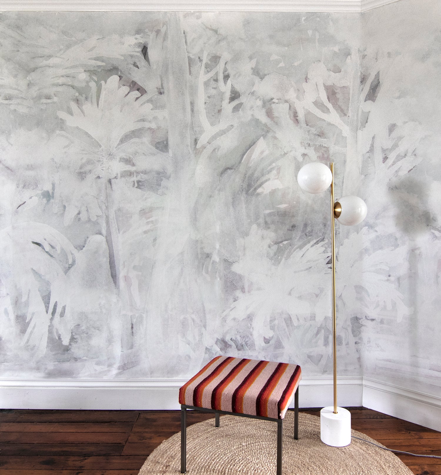 Room interior with abstract white wall design, striped stool, and floor lamp.