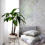 Room interior with a plant on a small table, radiator, and patterned cushions.