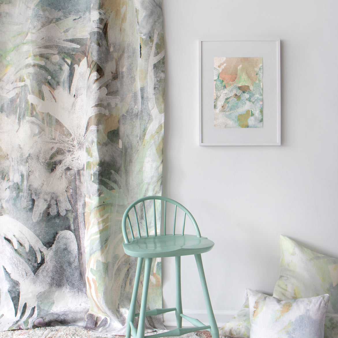 Green chair in a room with abstract art and decorative pillows on a white wall.