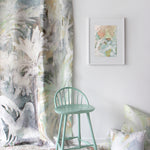 Green chair in a room with abstract art and decorative pillows on a white wall.