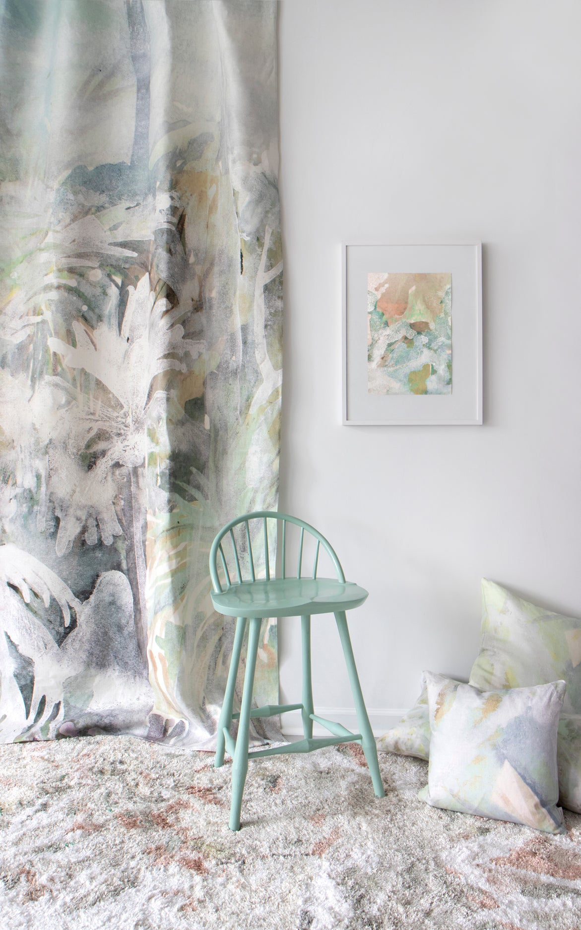 Green chair in a room with abstract art and decorative pillows on a white wall.