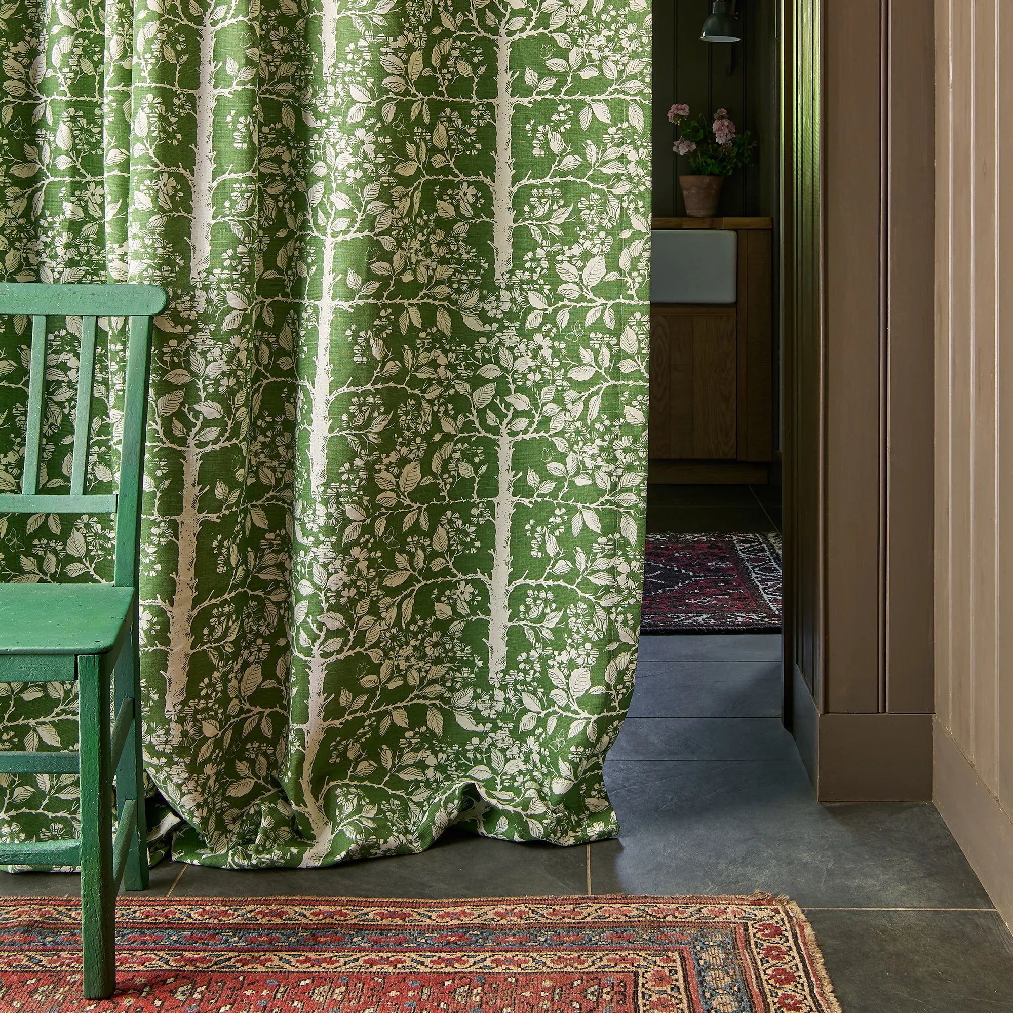 Green patterned curtain with a chair and rug in a room setting