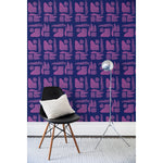 A chair and floor lamp in front of a wall papered in a large-scale pattern of abstract purple watercolor shapes on a dark purple background.