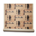 Partially unrolled wallpaper roll with layered geometric shapes in shades of black, beige and rust printed on a tan background.