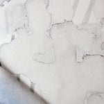 Draped fabric yardage in a watercolor watercolor print in shades of gray on a white field.