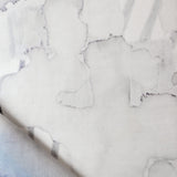 Draped fabric yardage in a watercolor watercolor print in shades of gray on a white field.