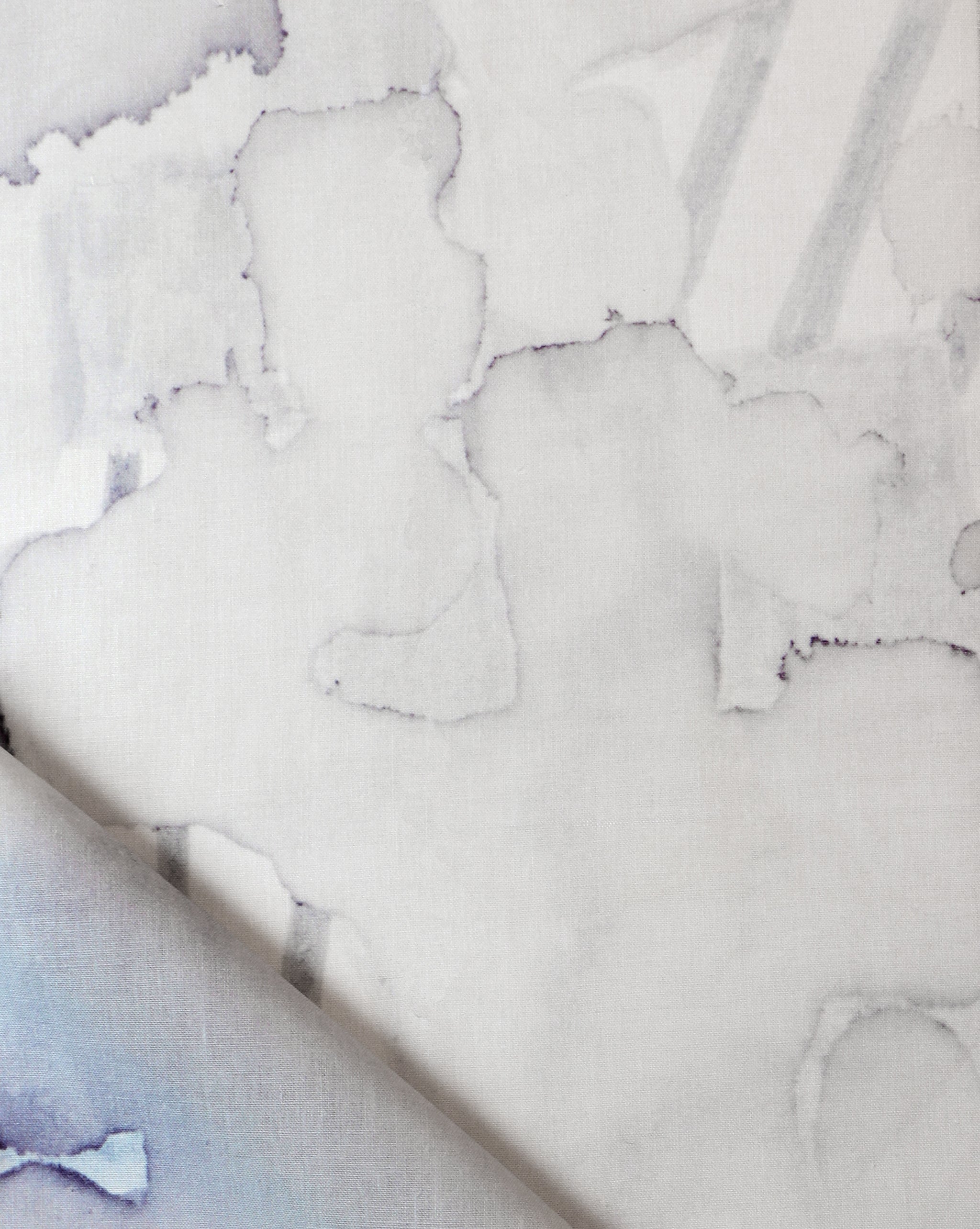 Draped fabric yardage in a watercolor watercolor print in shades of gray on a white field.