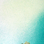 A vase of flowers stands in front of a wall covered in an abstract ombré paint splatter print in green, turquoise and white.