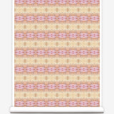Partially unrolled wallpaper yardage in a gridded paint splatter print in shades of pink, orange, yellow and white.