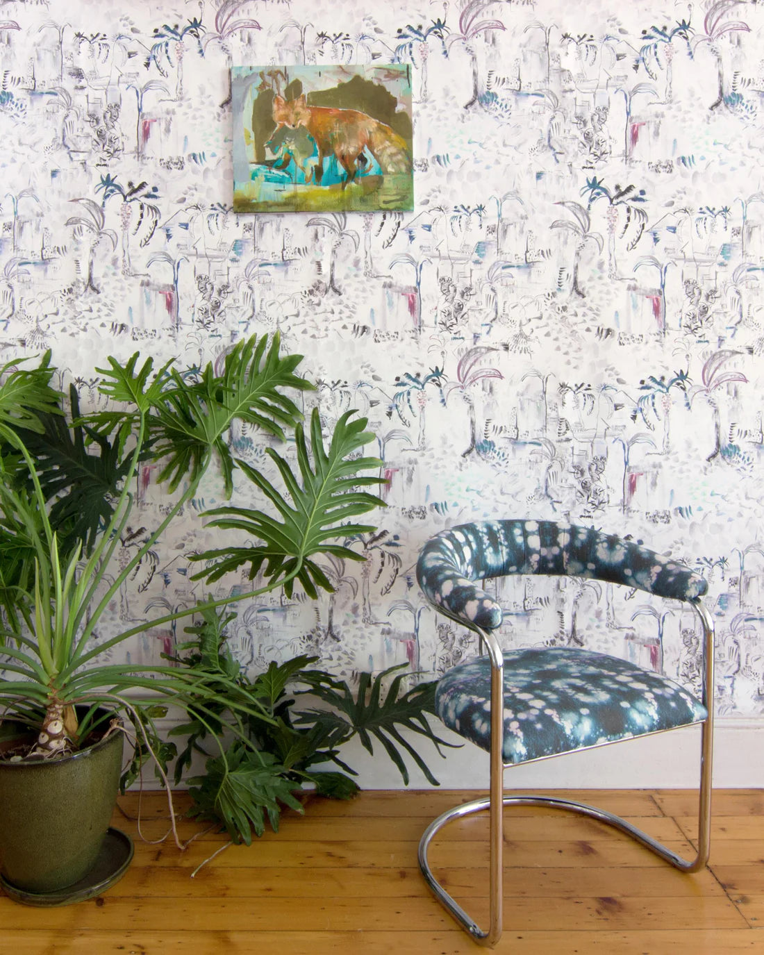 Modernist living tableau with a large plant and a statement wall papered in a painterly tree print.