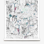 Partially unrolled wallpaper yardage in a painterly tree print in shades of gray, white, turquoise and pink.