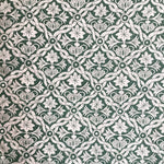 Detail of fabric in a floral lattice print in white on a dark green field.