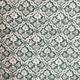 Detail of fabric in a floral lattice print in white on a dark green field.