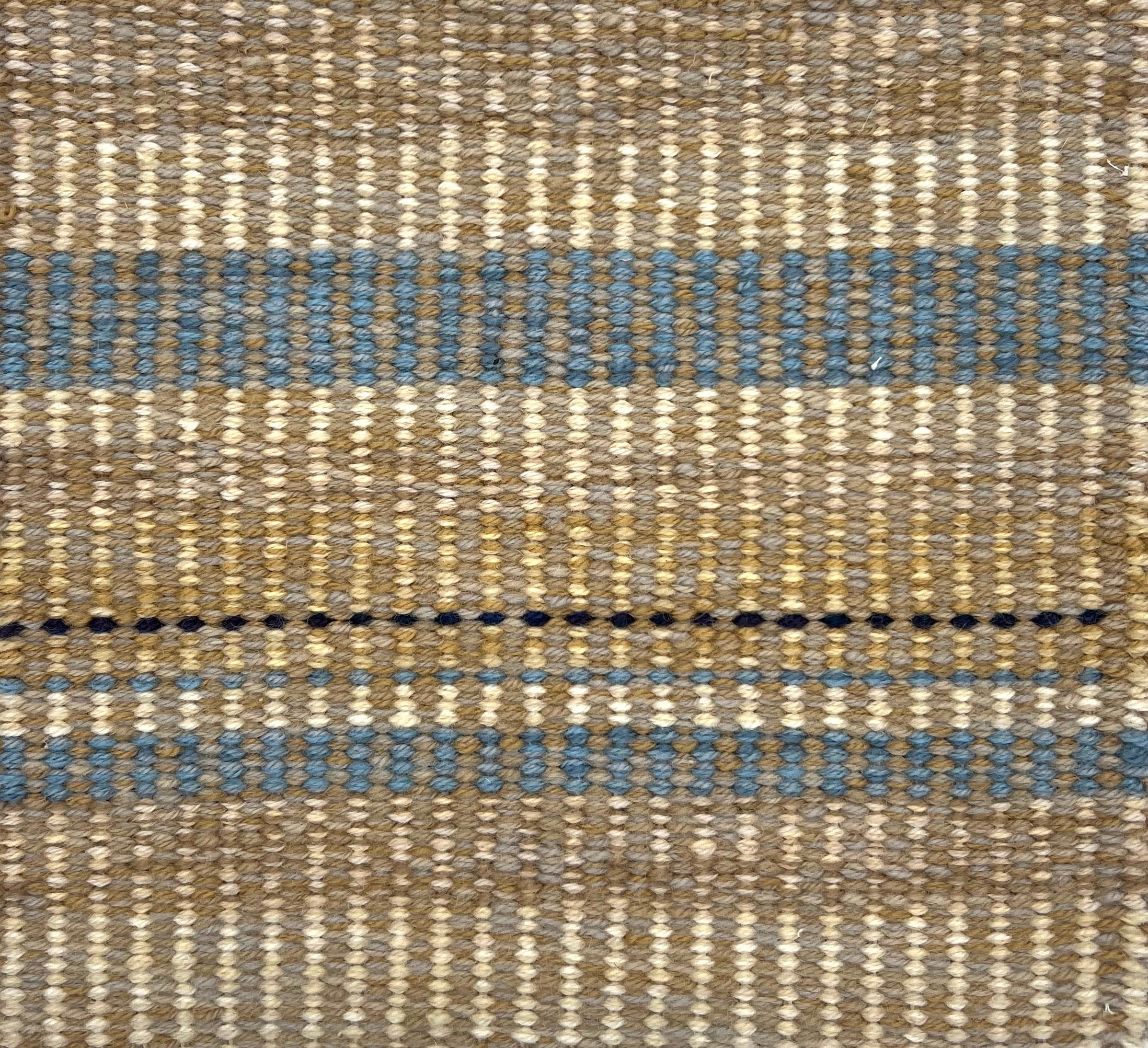 Textural flatweave rug in a varigated stripe in tan, cream and blue.