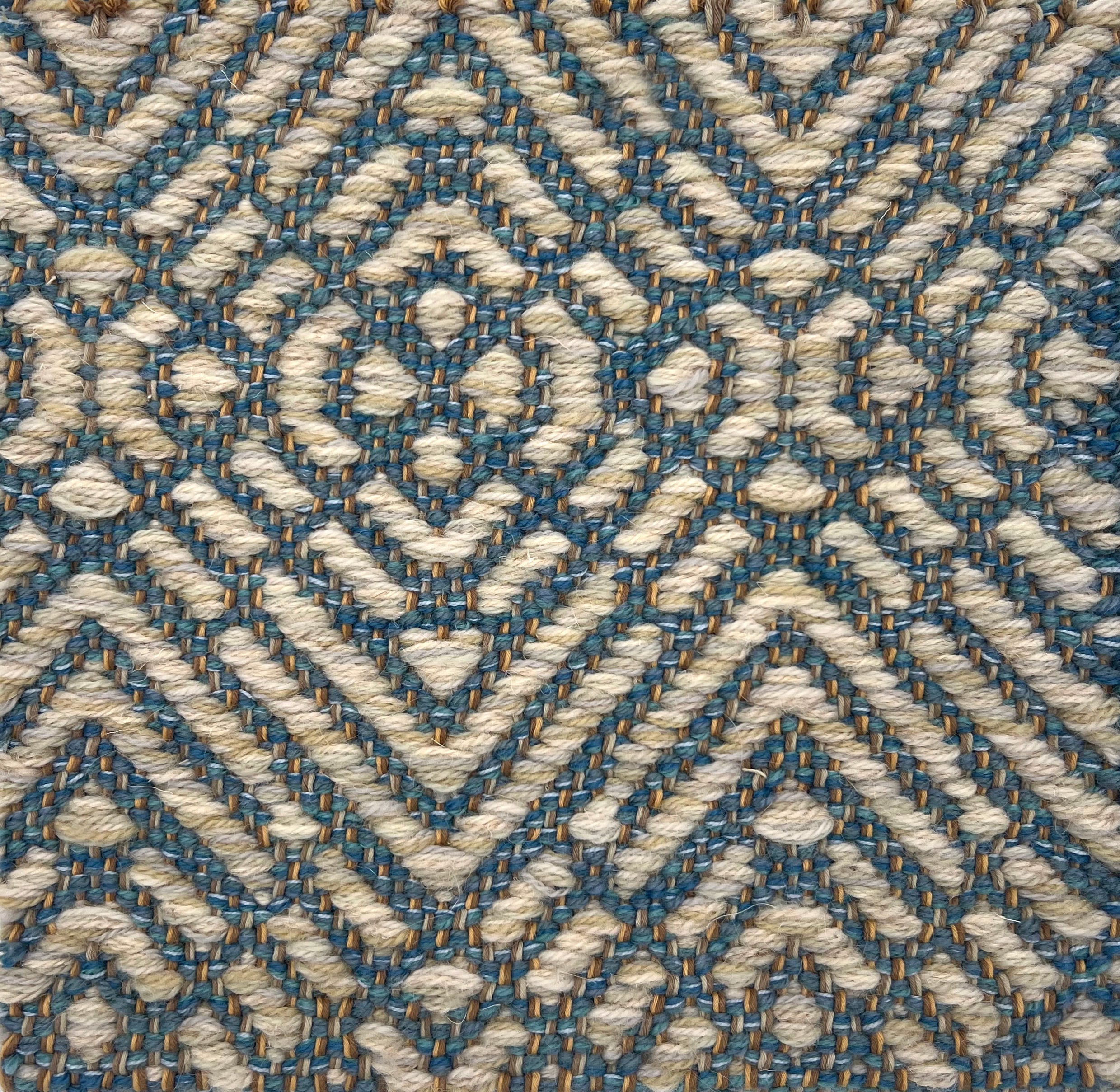 Textural flatweave rug in a raised diamond design in cream on a turquoise field.