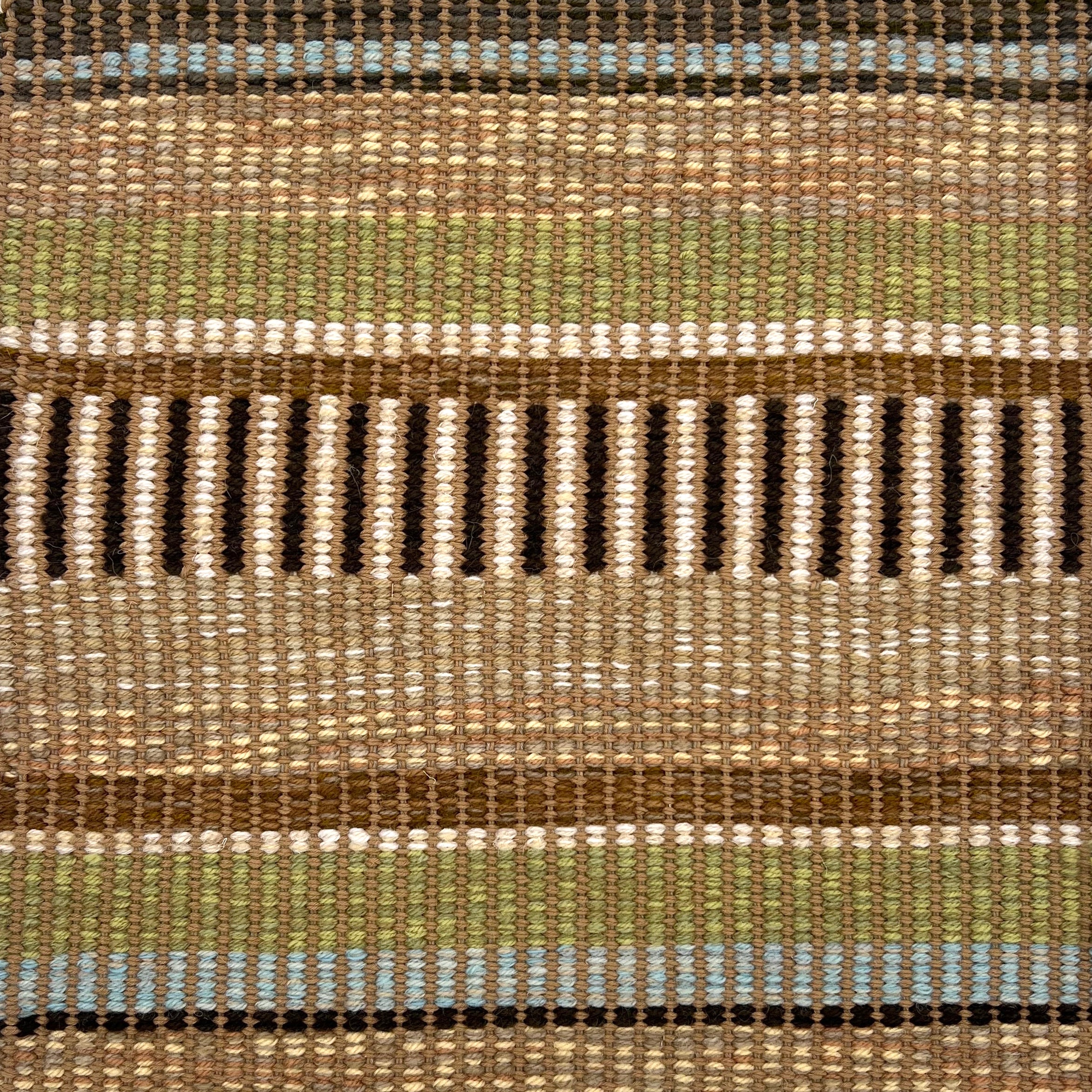 Textural flatweave rug in a varigated stripe in brown, tan, cream, green and blue.