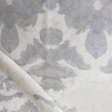 Draped fabric yardage in a watercolor ikat print in shades of gray on a greige field.