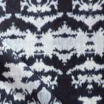 Draped fabric yardage in a watercolor ikat print in shades of blue and navy on a greige field.