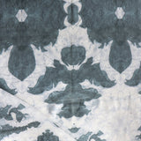Draped fabric yardage in a watercolor ikat print in shades of gray and navy on a cream field.