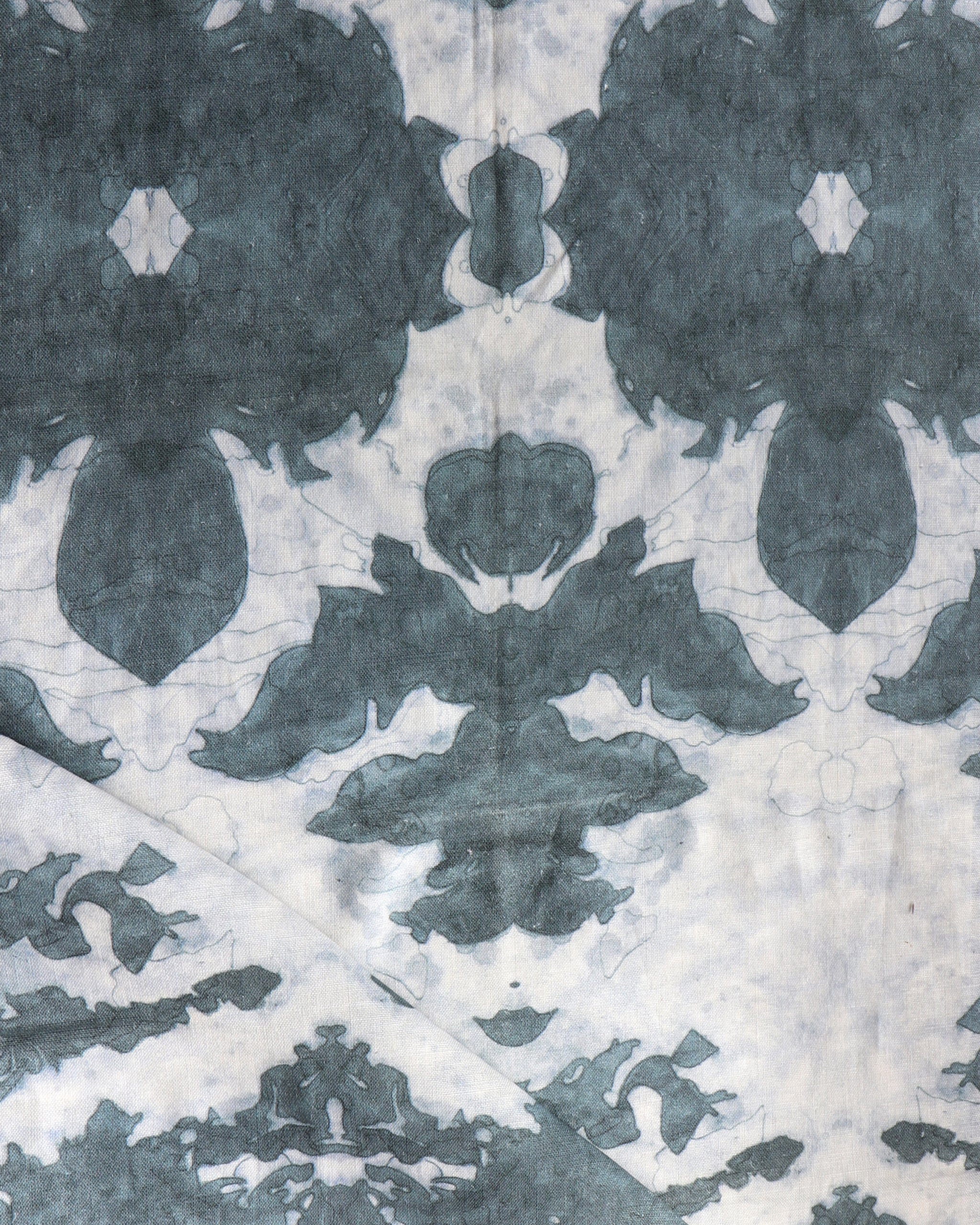 Draped fabric yardage in a watercolor ikat print in shades of gray and navy on a cream field.