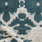 Draped fabric yardage in a watercolor ikat print in shades of turquoise and yellow on a cream field.