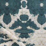 Draped fabric yardage in a watercolor ikat print in shades of turquoise and yellow on a cream field.