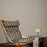Styled interior vignette with vintage wooden butterfly style chair with tan and black cushions, steel cube side table, retro glass lamp, dark wood floor and beige zebra patterned wallpaper. 
