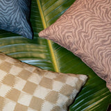 Styled flat-lay with detail of three throw pillows atop of a banana leaf with various patterns.