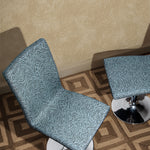 Overhead shot of two upholstered pestal chairs with a blue zebra pattern upholstery on a square patterned rug in brown against wallaper with white dots scattered on a tan field.