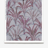 Partially unrolled wallpaper yardage in a painterly palm tree pattern in shades of purple and navy on a gray field.