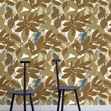 Two minimalist black chairs stand in front of a wall papered in a botanical and parrot print in bronze, brown, navy and yellow.