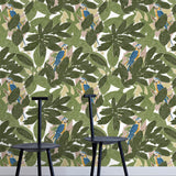 Two minimalist black chairs stand in front of a wall papered in a botanical and parrot print in green, blue and yellow.
