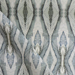 Draped fabric yardage in a watercolor diamond print in shades of gray and navy on a cream field.