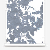 Partially unrolled wallpaper yardage in a watercolor floral print in shades of gray and blue on a white field.