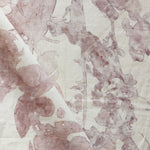 Draped fabric yardage in a watercolor tree print in pink and red on a cream field.