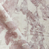 Draped fabric yardage in a watercolor tree print in pink and red on a cream field.