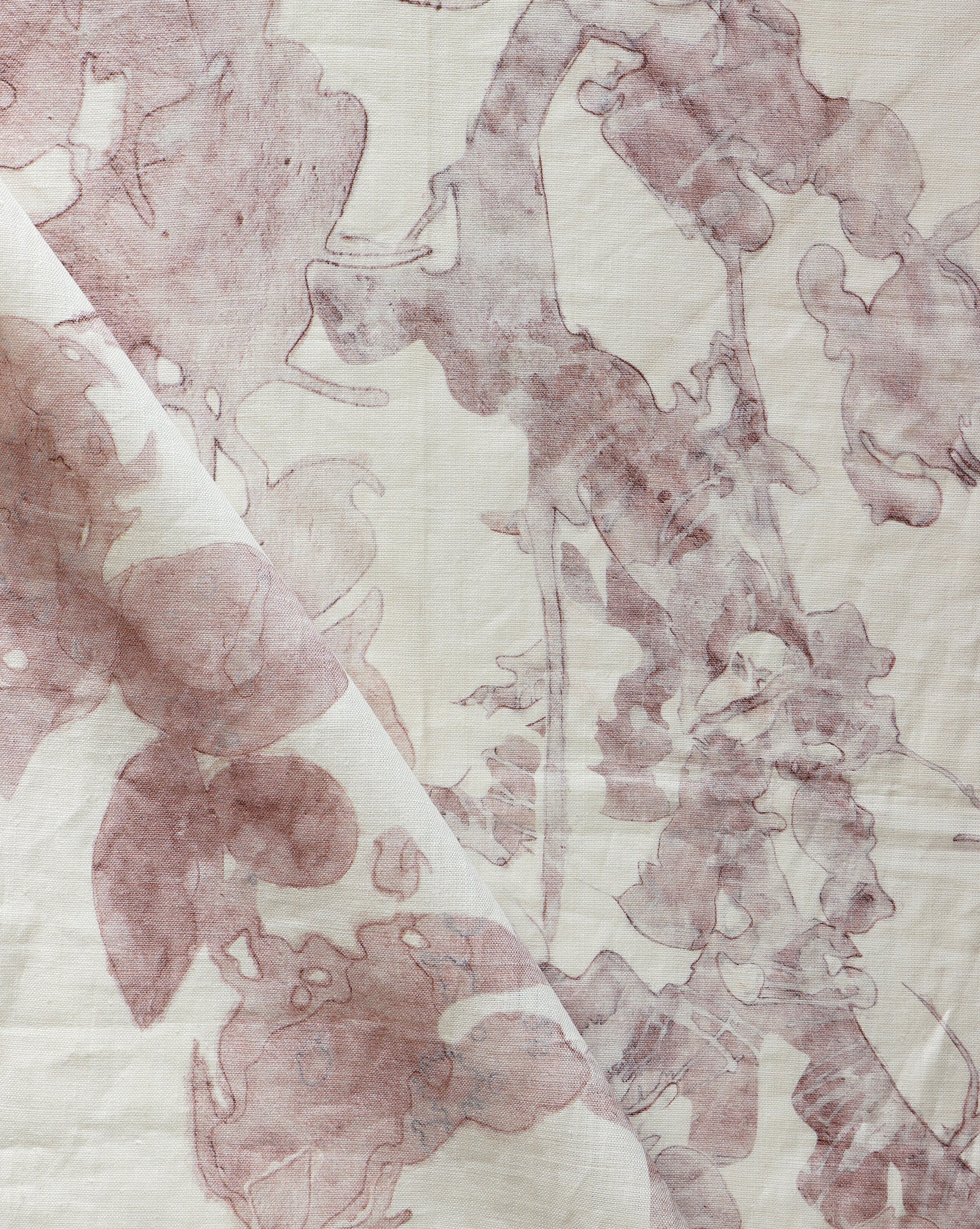 Draped fabric yardage in a watercolor tree print in pink and red on a cream field.