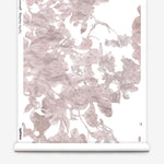 Partially unrolled wallpaper yardage in a watercolor floral print in mottled pink and gray on a white field.