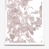 Partially unrolled wallpaper yardage in a watercolor floral print in mottled pink and gray on a white field.