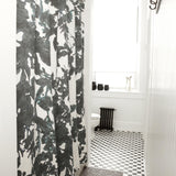 A bathroom with black and white subway tiles and a shower curtain in a watercolor black and white tree print.