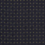Detail of an embroidered fabric in a dashed basketweave design in navy blue with green accents.