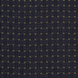 Detail of an embroidered fabric in a dashed basketweave design in navy blue with green accents.